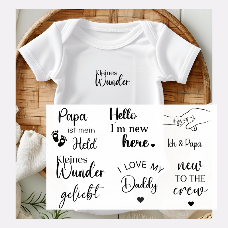 Set von 7 Baby-Bügelbildern in Schwarz mit süßen Motiven: „Papa ist mein Held“ mit Füßen und Herzen, „Hello, I’m new here“, „Ich & Papa“ mit Händen, „Kleines Wunder“, „Geliebt“, „I love my daddy“ mit Herz, „New to the crew“ mit Herz. Perfekt für Babyparty oder als Vatertagsgeschenk.