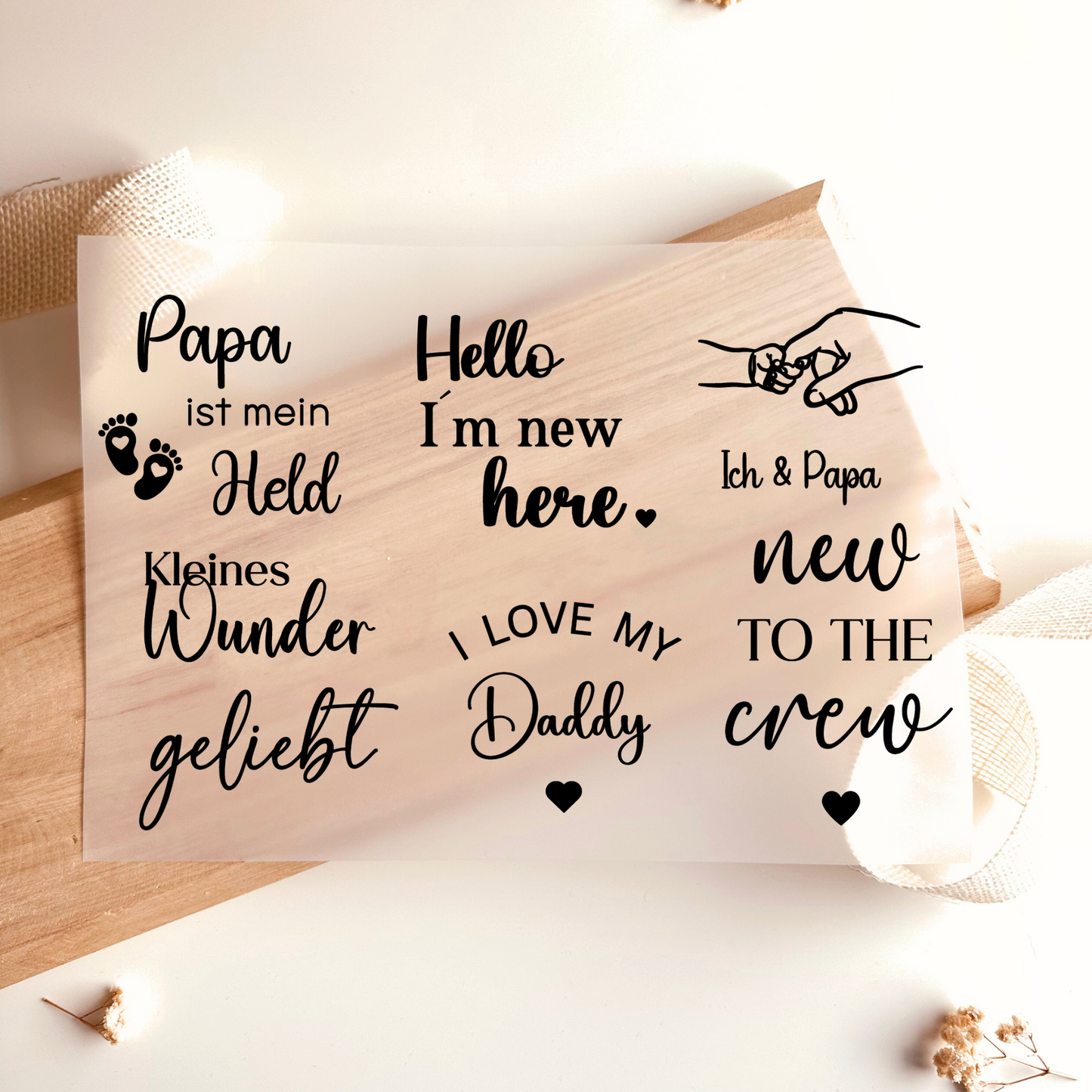 Bügelbild-Set mit Baby-Sprüchen wie "Hello I'm New Here", "Kleines Wunder" und "Papa ist mein Held" in Schwarz