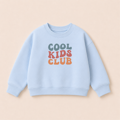 Bügelbild Cool Kids Club im Retro-Schriftzug in Blaugrau, Rosé und Orange, aufgebügelt auf hellblauem Kinder-Sweatshirt