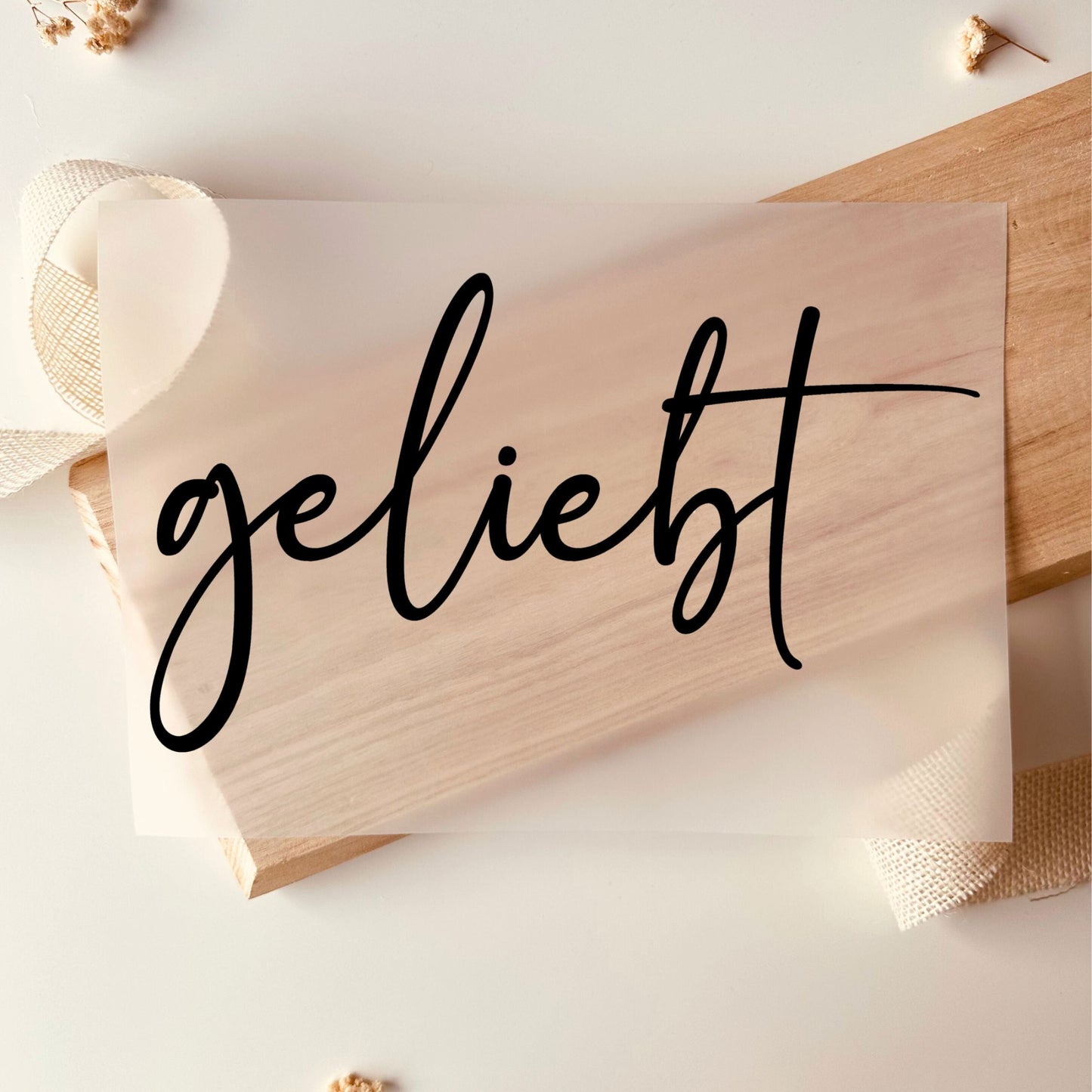 Bügelbild-Transferfolie mit Schriftzug "geliebt" in schwarzer Schreibschrift