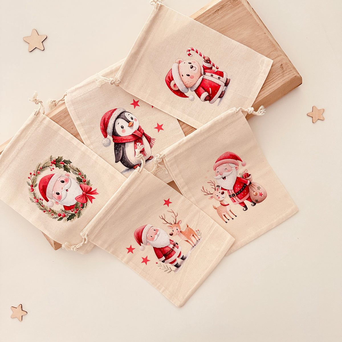 Bügelbild Set Weihnachten auf Stoffsäckchen aufgebügelt: Weihnachtsmann mit Rentier, Pinguin, Teddy mit Zuckerstange und Kranz. DIY Adventskalender und Geschenkverpackung