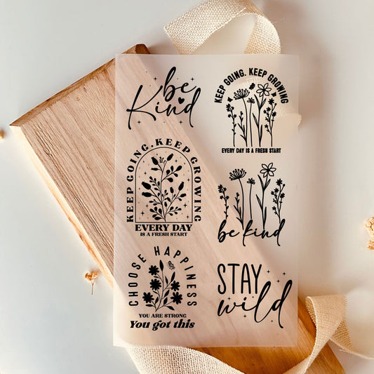 Bügelbild-Set mit floralen Strichzeichnungen und Sprüchen wie "Be Kind", "Stay Wild" und "Keep Going, Keep Growing" in Schwarz
