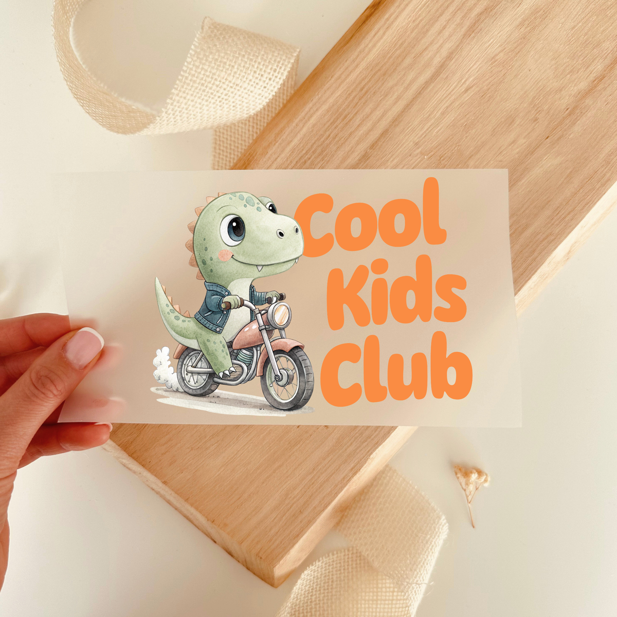 Cool Kids Club Aufbügler mit Dino auf Motorrad in der Hand gehalten vor Holzbrett