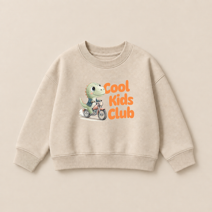 Cool Kids Club Bügelbild mit grünem Dino auf Motorrad in Jeansjacke auf beigem Kinderpullover