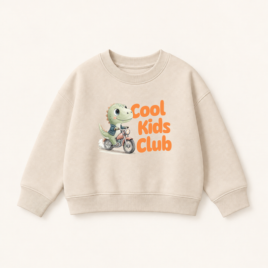 Cool Kids Club Bügelbild mit grünem Dino auf Motorrad in Jeansjacke auf beigem Kinderpullover